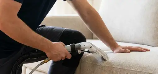 Professional upholstery cleaner deep-cleaning a fabric sofa with a handheld extraction tool, New Orleans, LA.